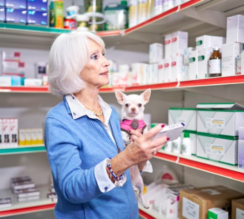 A woman at a vet pharmacy getting medication for her dog